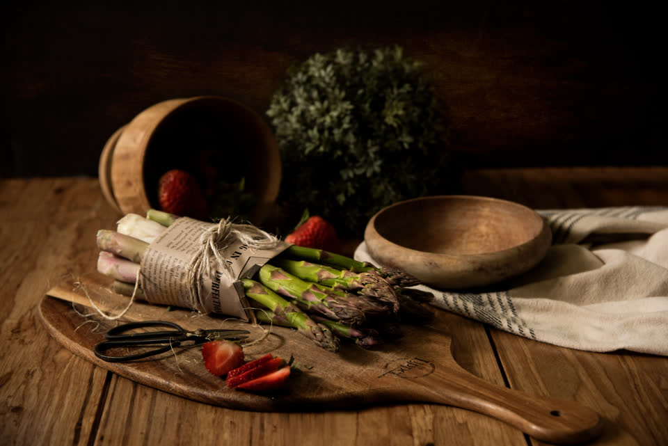 Fresh asparagus, strawberries and a wooden board on a rustic table